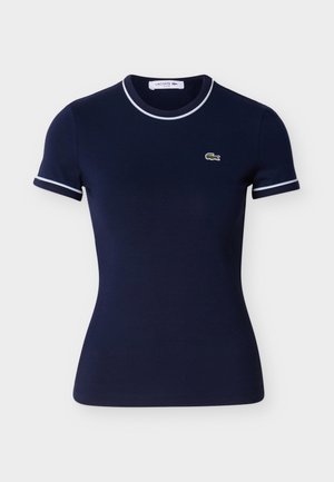 Tricou din bumbac albastru marin cu mâneci scurte, având margini albe la guler și mâneci, și un mic logo Lacoste verde.
