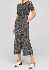 Marintröja med ljusbeige prickmönster, korta ärmar och vida ben. Tillverkad av texturerad tyg. Har sidofickor.