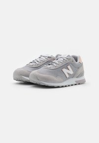 Gray athletic shoes featuring a mesh upper, suede accents, and a rubber sole. Notable details include a light pink heel tab and logo.