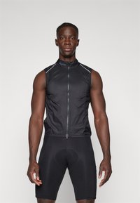Gilet de cyclisme sans manches noir avec fermeture éclair, accents réfléchissants, et en matériau léger, associé à un short de cyclisme matelassé noir.