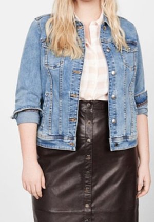 Blonde woman wearing rolled-up sleeve denim jacket, light plaid shirt, and buttoned black leather skirt.