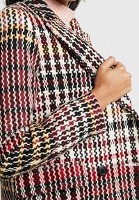 Blazer z vlněné směsi s vícebarevným kostkovaným vzorem v červené, černé, bílé a žluté barvě, se záklopkou a zapínáním na knoflík.