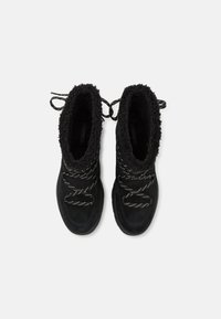 Bottes en velours noir avec doublure en polaire noire texturée, dotées de lacets blancs contrastants et d'un design à bout rond. Adaptées aux temps froids.