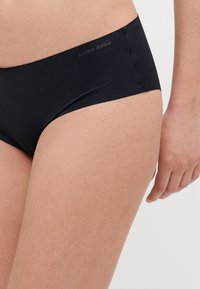 Čierne bikini spodky s hladkým povrchom, nízkym strihom, plochými švami a decentným logom Björn Borg na boku.
