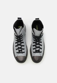 Wysokie sneakersy z szarej płótna z czarnymi sznurowadłami. Posiadają gumowy czubek i kontrastowe zielone logo na wkładce. Teksturowana czarna podeszwa.