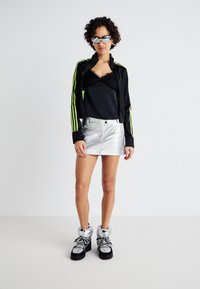 Black jacket with green stripes, black top with lace, shiny silver mini skirt, and chunky black and silver boots with laces.