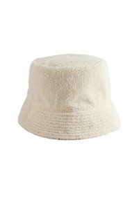 Cream-colored bucket hat made of textured fabric with a soft, plush feel. Features a rounded crown and a wide, downward-sloping brim.