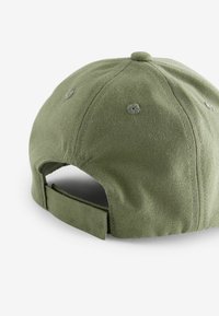 Cappellino da baseball in tela verde con retro strutturato, strap in tessuto regolabile e fori di ventilazione. Presenta cuciture tonali e bottone superiore.