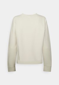 Sudadera color crema con mangas largas, cuello redondo y puños de canalé. Textura suave, diseño minimalista, sin logotipos ni patrones visibles.