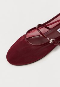 Sandalo piatto bordeaux con tomaia in rete, sottile cinturino e dettagli con fibbia classica. Soletta morbidamente texturizzata e suola piatta per il massimo comfort.