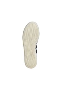 Zapatilla blanca con rayas negras y suela texturizada. Presenta una parte superior lisa y una suela de goma con un patrón de espiga para mayor tracción.