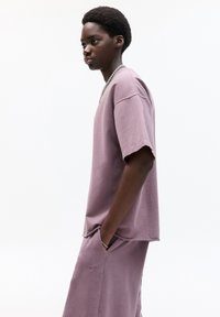 Paarse katoenen oversized t-shirt met korte mouwen, textuurafwerking, zijzak. Gepaard met bijpassende onderkant, met subtiele logo-details.