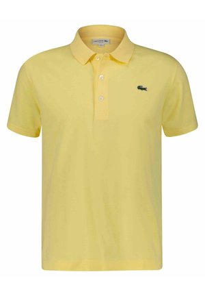 Polo à manches courtes jaune avec trois boutons et un petit logo de crocodile vert sur la poitrine gauche.