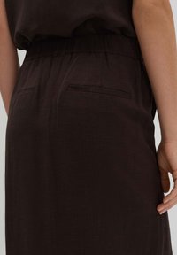 Robe en lin marron à coupe décontractée, avec une taille élastique, deux poches arrière et un tissu texturé.