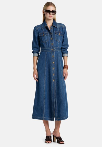 Denim ingruha hosszú ujjakkal, gombos elülső résszel, két mellzsebbel, megkötős derékkal és árnyékolt szoknyával. Kék anyag, arany gombokkal kiemelve.