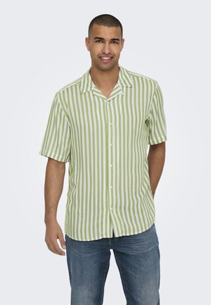 Groen en wit gestreept overhemd met korte mouwen en een kraag, met knopen aan de voorkant; gecombineerd met blauwe jeans.