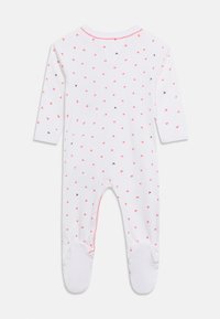 Λευκό παιδικό φορμάκι με μακριά μανίκια και ποδαράκια, διακοσμημένο με μικρές ροζ καρδιές διάσπαρτες και διακριτική ροζ λεπτομέρεια γύρω από τη λαιμόκοψη και τα ποδαράκια.