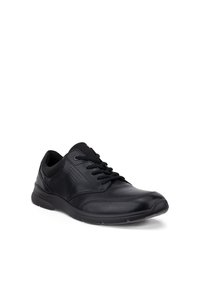 Baskets décontractées en cuir noir avec lacets à l’avant, col matelassé, détails perforés sur les côtés et semelle en caoutchouc texturée inclinée vers la droite.