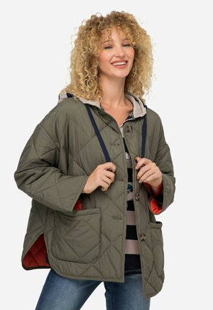 Gequilte olijfgroene jas met een capuchon, voorzien van grijze accenten, twee voorzakken en een felrode voering. Knoopsluiting met koorddetail.