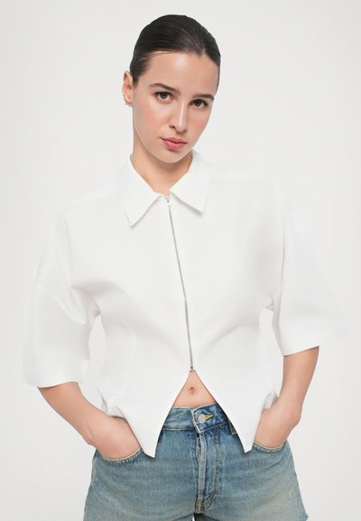 Witte short-sleeve shirt met een puntige kraag en een voorneerrits. Textuurstof met een cropped ontwerp, gecombineerd met high-waisted denim shorts.