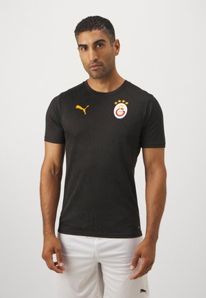 Maglietta sportiva nera a maniche corte con un motivo testurizzato, dotata di un logo Puma giallo e un emblema di club rosso e bianco con stelle.