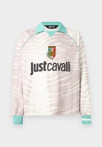 Μπλούζα μακρυμάνικη σε μπεζ και λευκό με τύπωμα ζέβρας, γιακά και μανσέτες σε τυρκουάζ, με λογότυπο Just Cavalli και πολύχρωμο έμβλημα στο στήθος.