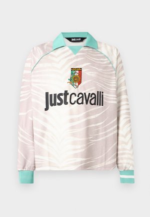 Camicia a maniche lunghe beige e bianca con stampa a zebra, colletto e polsini turchesi, con logo Just Cavalli e emblema colorato sul petto.