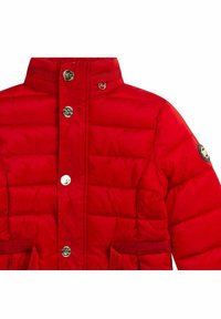 Chaqueta acolchada roja con un alto cuello, botones en tono dorado y bolsillos laterales a juego. Presenta la marca cerca del cuello y en la manga izquierda.