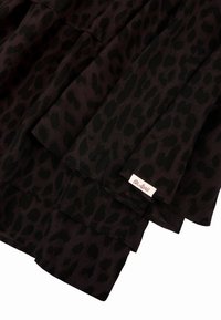 Tela de estampado de leopardo negro y púrpura oscuro con volantes en capas y una etiqueta que dice "Oh-April" en rosa. Textura suave y ligera.