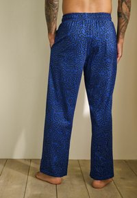 Zilie pidžamu bikses ar melnu abstraktu rakstu, ar elastīgu jostasvietu un taisnām kājām. Audums izskatās gluds ar vieglu spīdumu.