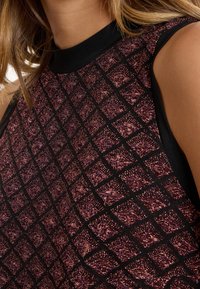 Zwarte mouwloze top met een gestructureerd paars ruitpatroon, voorzien van een hoge halslijn en een gladde afwerking langs de kraag en armsgaten.