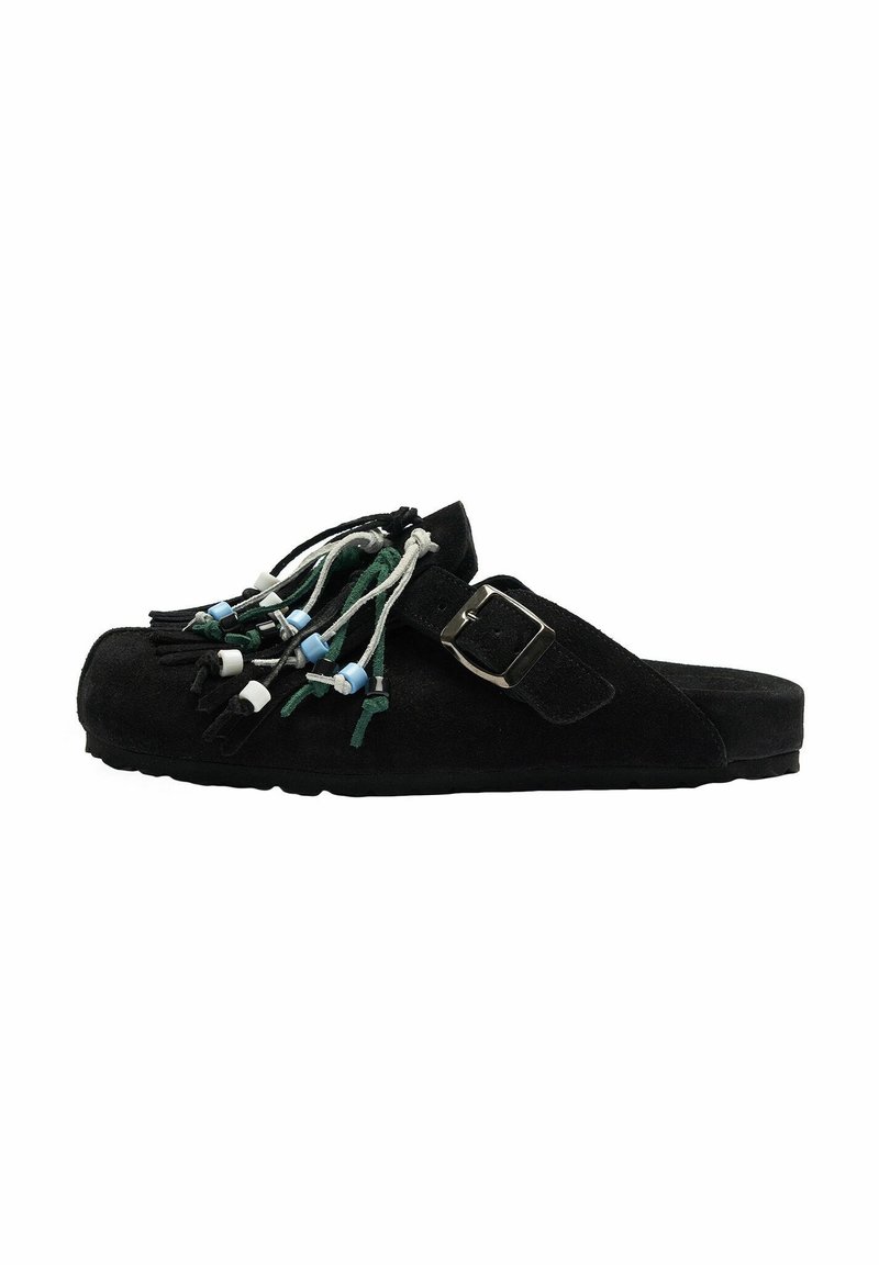 Chaussure noire à enfiler avec une boucle latérale, décorée de cordons multicolores et de perles suspendus sur le dessus, semelle plate, texture en daim.
