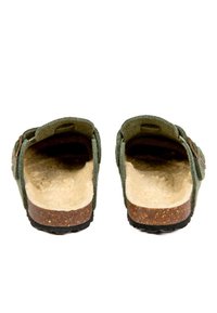 Des chaussures slip-on en feutre vert avec une semelle en liège, un intérieur doux, une sangle ajustable et deux boutons décoratifs de chaque côté.