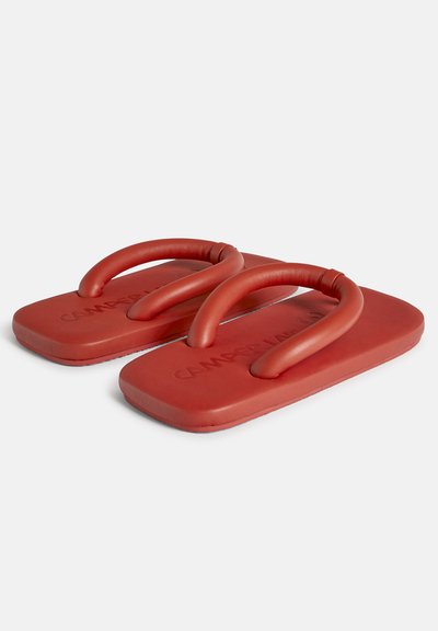 Røde gummiflip-flops med en struktureret overflade og dobbelte løkker til fodbånd, designet til komfort og afslappet brug.