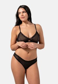 Set di lingerie nera trasparente composto da un bralette con bordo in pizzo e una mutandina coordinata. Spalline regolabili e delicati accenti in pizzo. Texture liscia.