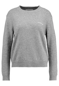 Gråstickad tröja med rundad halsringning, ribbade ärmslut och nederkant. Har en liten vit logotyp på bröstet. Mjuk textur, avslappnad passform.