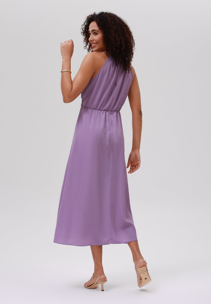 Lila satijnen jurk met een halternek, een getailleerde taille en een vloeiende A-lijn rok. Draag met beige sandaaltjes met bandjes. Zachte textuur, elegante uitstraling.
