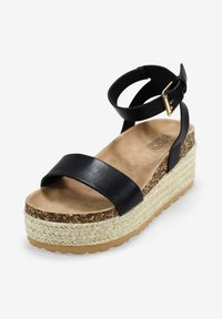Sandalias de plataforma de cuero negro con una suela intermedia de yute trenzado, correa ajustable en el tobillo y una plantilla suave y acolchada.