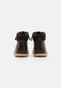 Brown leather ankle boots with a soft, dark brown wool collar, lace-up design, and light brown rubber sole with ridges for traction.
