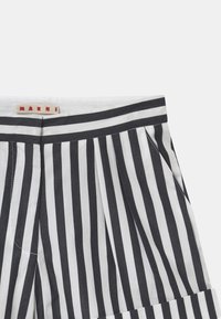 Svarta och vita randiga byxor med en midjeband som har en Marni-etikett, veck och sidofickor. Materialet verkar lätt och strukturerat.