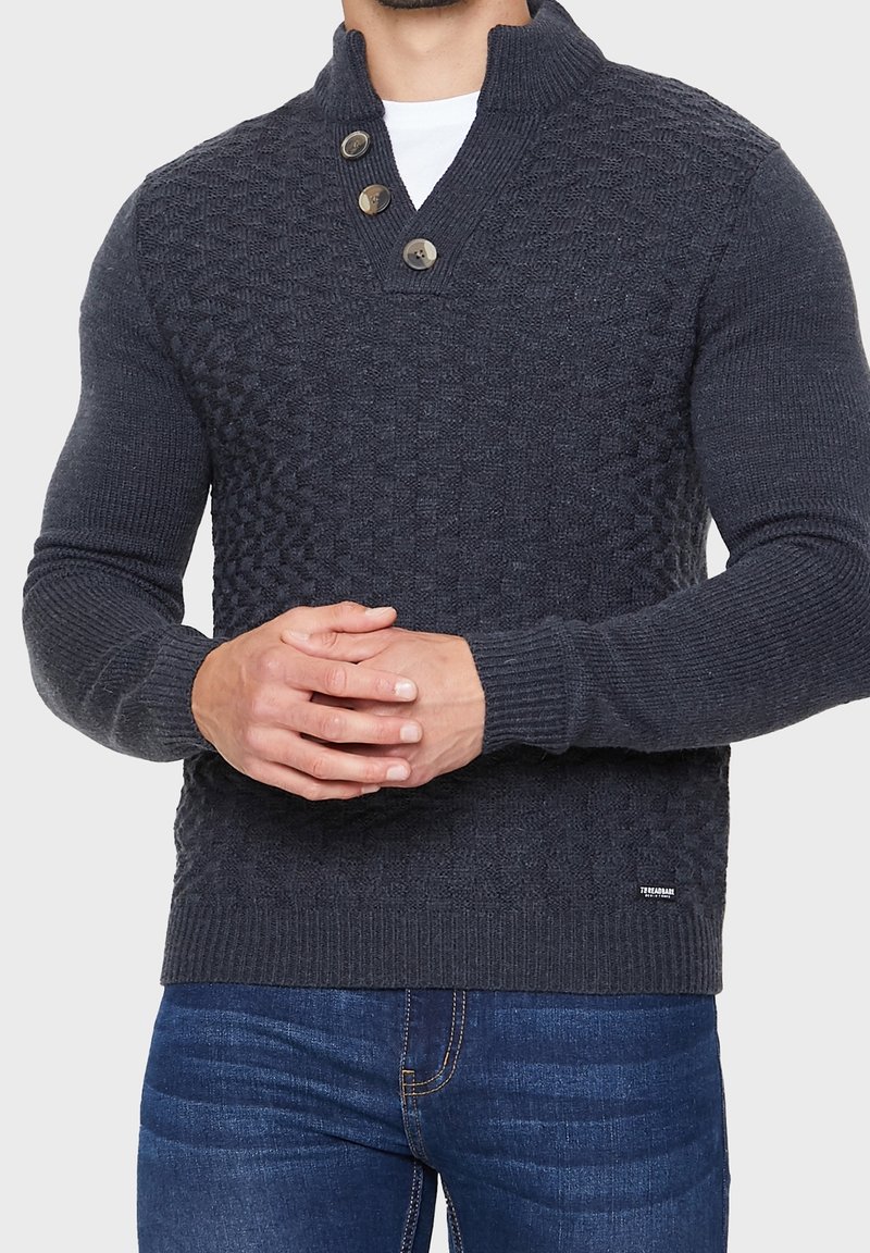 Donkergrijze gebreide pullover met een gestructureerd patroon op de bovenkant, drie knopen bij de kraag en geribbelde manchetten en zoom.