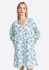Blumenmusterkleid mit V-Ausschnitt, Dreiviertelärmeln und Taschen. Der Stoff zeigt blaue Blumen auf einem hellen Hintergrund mit grünen Akzenten.