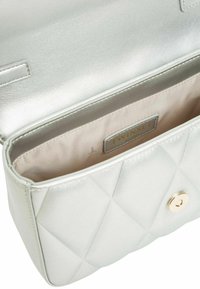 Borsa a tracolla trapuntata in metallo color argento con chiusura a scatto, fodera interna liscia e etichetta di marca visibile all'interno.