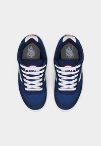 Ζευγάρι από ναυτικό μπλε αθλητικά παπούτσια Vans με λευκά κορδόνια και σόλες, φωτογραφημένα από πάνω σε λευκό απλό φόντο.