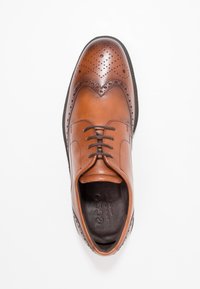 Chaussure habillée en cuir marron avec des détails brogue, un bout arrondi et un design à lacets. Présente une finition lisse et des accents texturés sur le talon.
