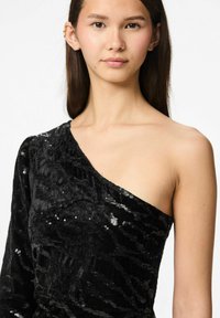 Juodas, vieno peties suknelė iš tekstūruoto audinio, dekoruota blizgučiais. Pritaikytas siluetas akcentuoja petį ir kaklą.