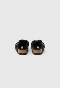 Juodi batai su tekstūruotu audinio viršumi, kamštiniu vidpadžiu ir minkšta pamušalu. Turi reguliuojamą dirželį geresniam pritaikymui. Minimalistinio dizaino.