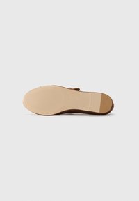 Brown sandal with a rounded toe, textured tan rubber sole, and a simple buckle strap design. Flat and suitable for casual wear.