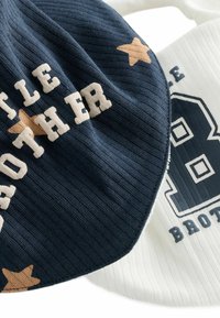 Två babymössor: en marinblå ribbad med "LITTLE BROTHER" i kräm och en stjärndetalj; den andra vit med en blå "8" och textdetalj.
