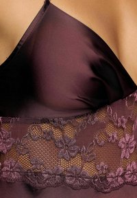 Prenda de satén burdeos con acentos de encaje floral en la cintura. Textura suave con tirantes ajustables y un escote profundo.